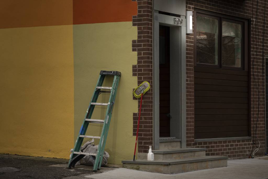 Night view of house painted with large blocks of color,  a ladder and mop leaning against a wall.