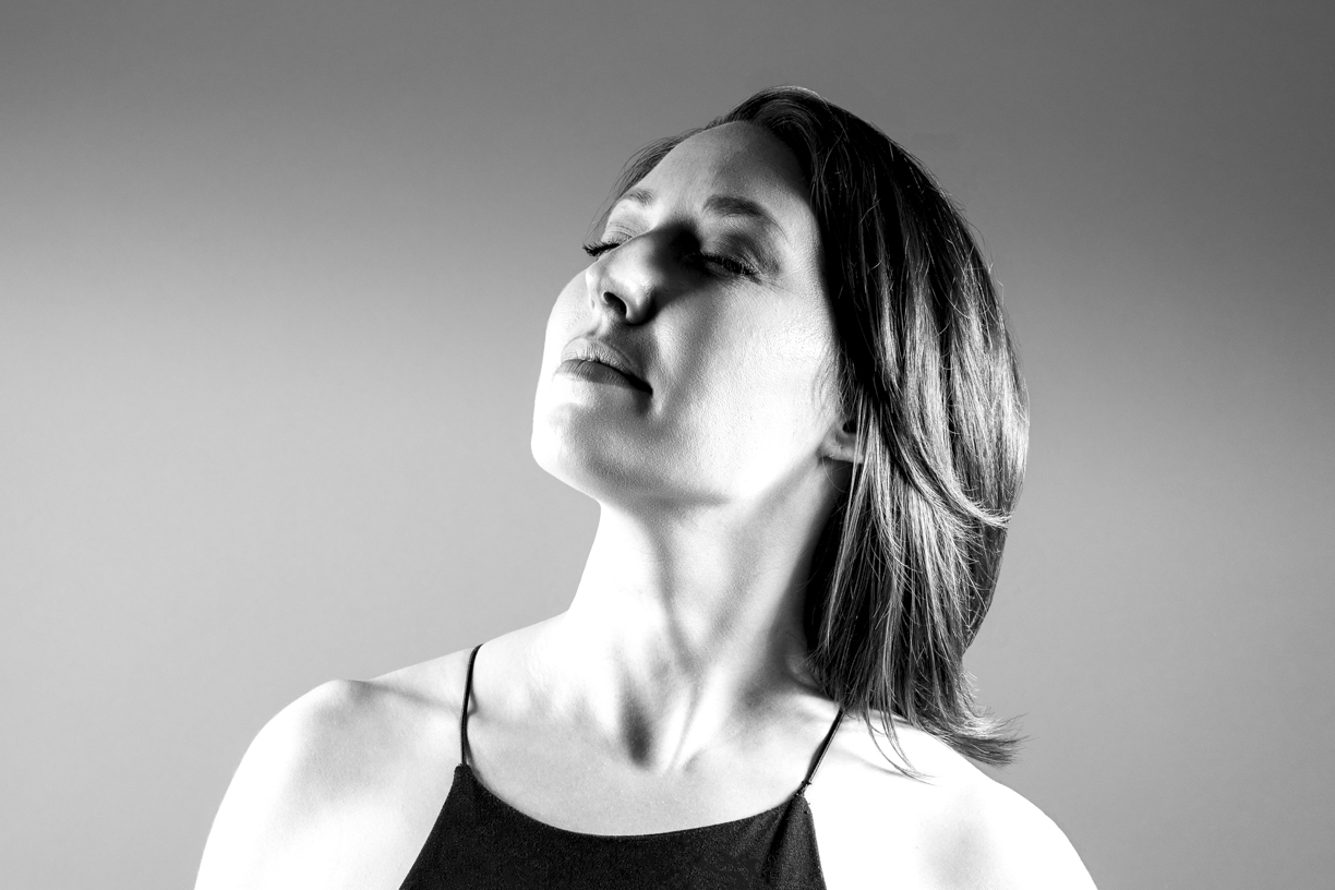 Black and white portrait of beautiful brunette facing upward with eyes closed.