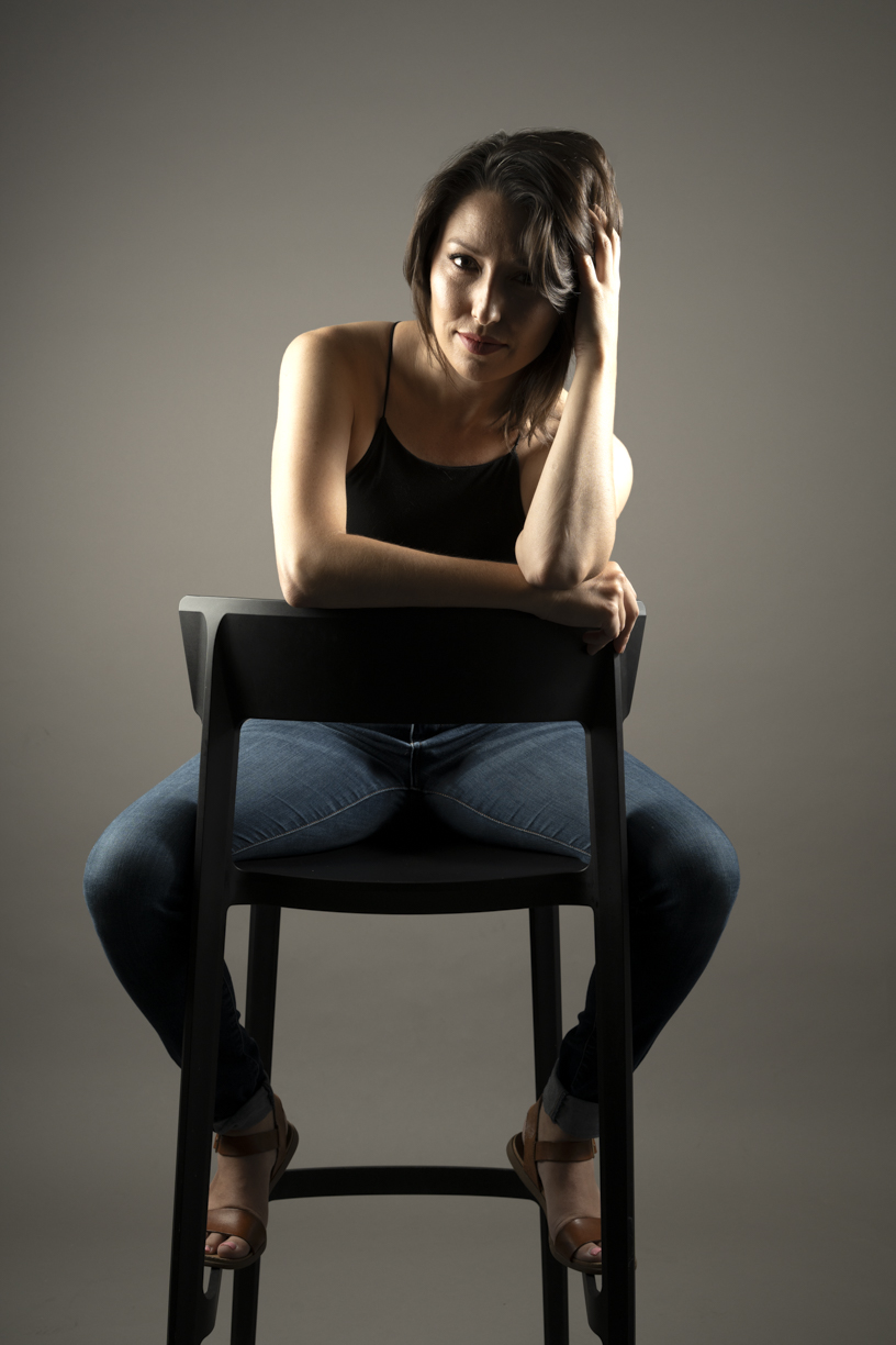 Color photo of beautiful brunette female model on reversed chair
