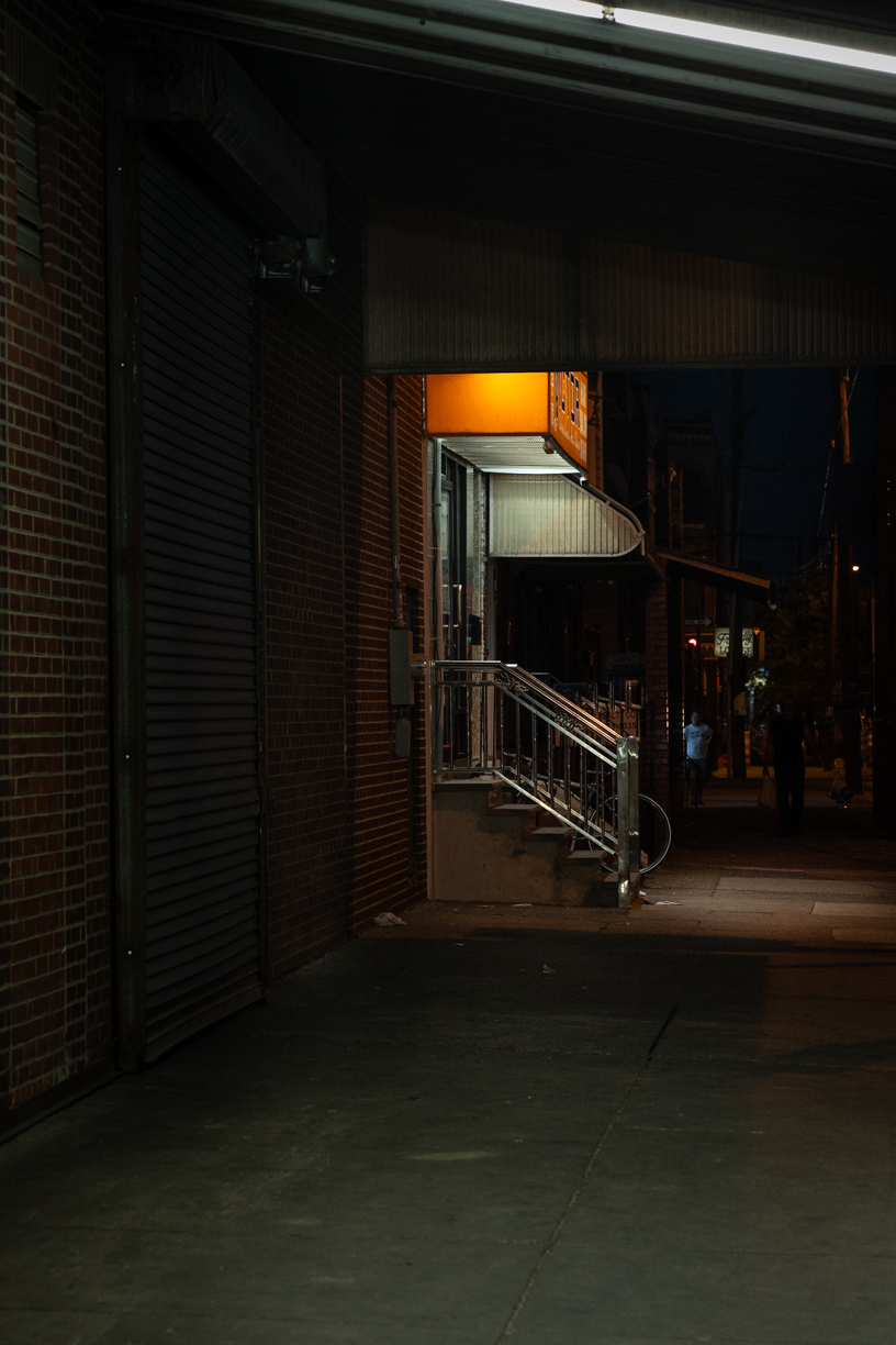 Night view of short stairway topped with orange sign leading into building.